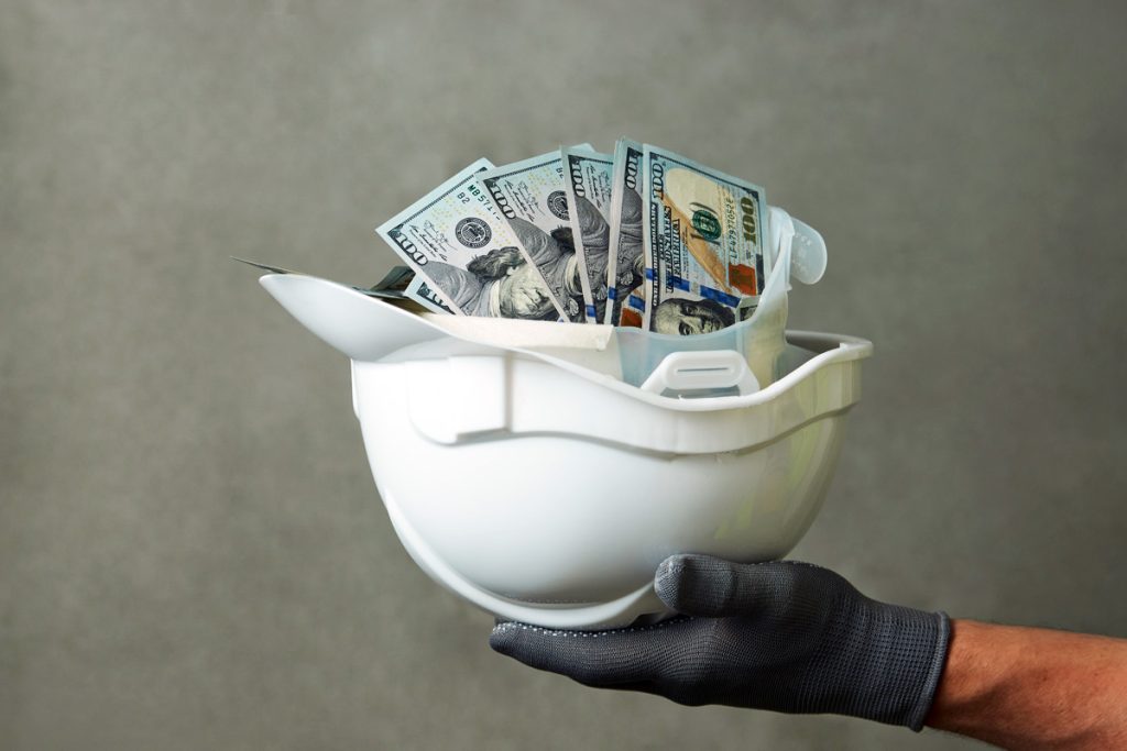 money inside a construction helmet being held by a hand upside down